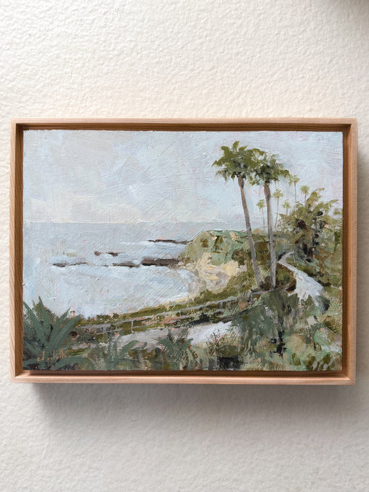 An acrylic painting in a floater wood frame, depicting the view of Treasure Island from the Montage Resort in Laguna Beach, CA. 